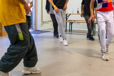 Man sieht sechs Paar beine, sie Tanzen.