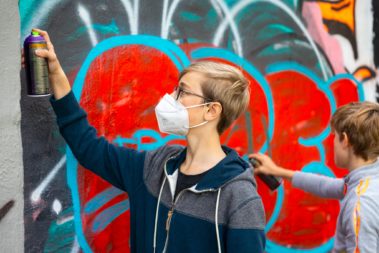 Zwei junge Menschen sprühen Graffiti
