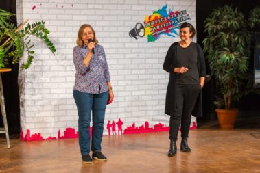 Ursula Holtmann-Schnieder sprich ins Mikrofon, rechts daneben steht Paula Elsholz die sie anschaut